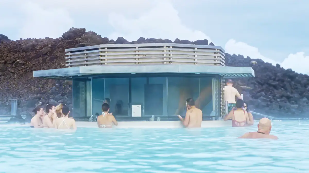 Touristes profitant du bar dans le Blue Lagoon en Islande, entourés d’eaux thermales bleu laiteux et d’un paysage volcanique. Un lieu parfait pour se détendre lors d’un voyage en camping-car.