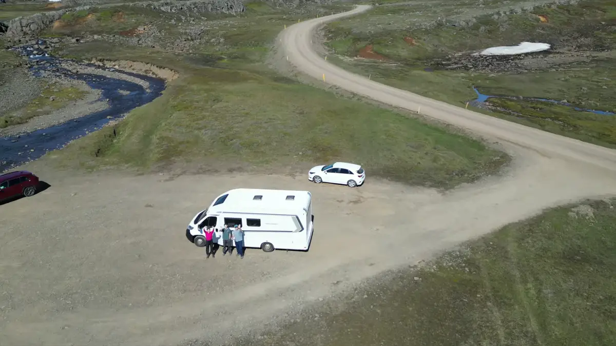 Camping-car stationné sur un chemin isolé en Islande avec un groupe de voyageurs profitant du paysage. La liberté de parcourir l'Islande en camping-car permet d'explorer des coins hors des sentiers touristiques.