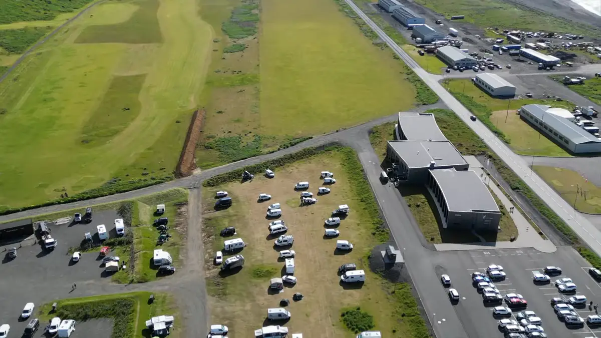 Camping en Islande avec plusieurs camping-cars stationnés dans une zone désignée, entouré de nature et de structures modernes. Choisir les bons campings est essentiel pour un voyage confortable et sans soucis en camping-car.