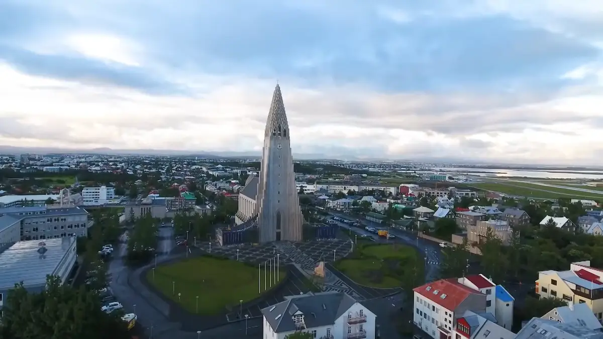 Vue aérienne de Hallgrímskirkja, l’église emblématique de Reykjavik, avec la ville et l’aéroport en arrière-plan. Un point de départ idéal pour un road trip en camping-car en Islande.
