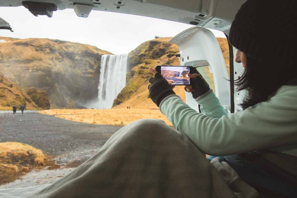 Touriste prenant une photo de la cascade Sk&oacute;gafoss depuis l&rsquo;int&eacute;rieur d&rsquo;un camping-car