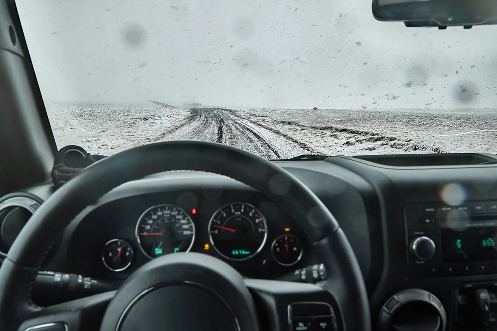 Vue depuis l’intérieur d’une voiture roulant sur une route enneigée en Islande.
