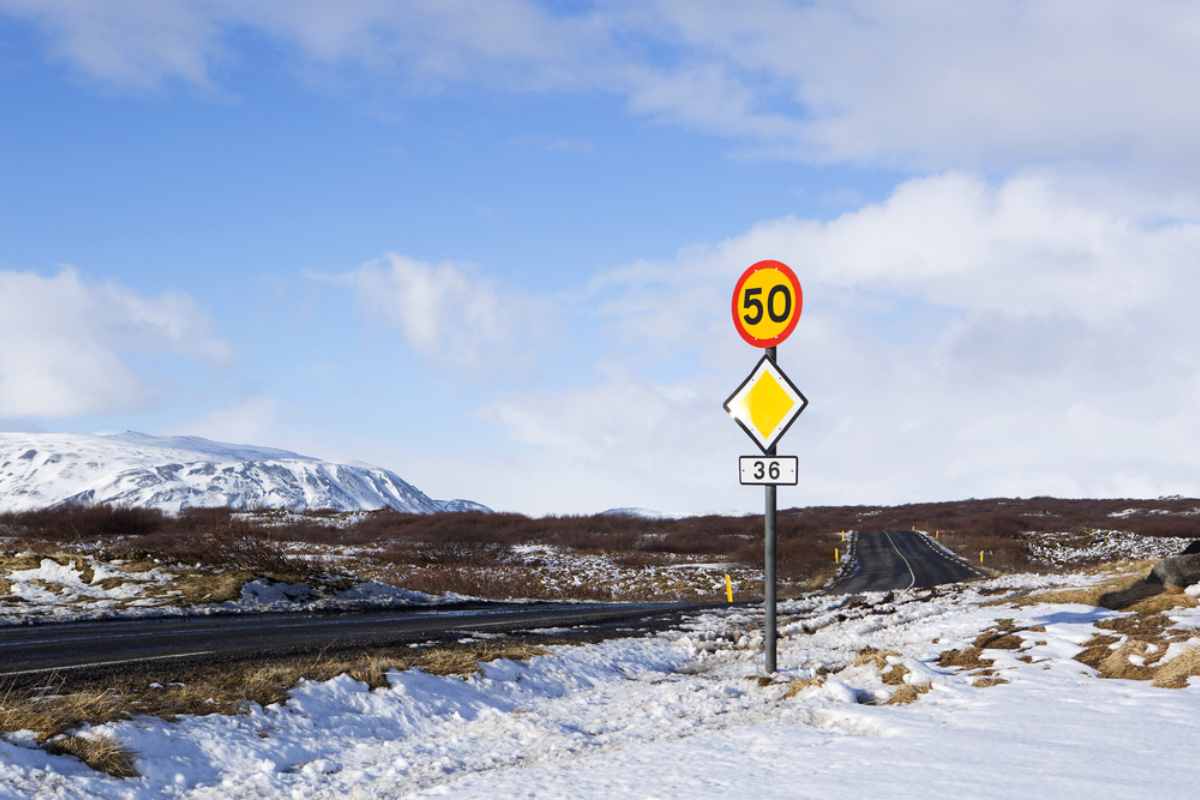 Route ouverte en Islande avec des montagnes escarpées en arrière-plan et un panneau de limitation de vitesse